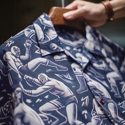 Close-up of a blue shirt with white graphic designs, held by a person.